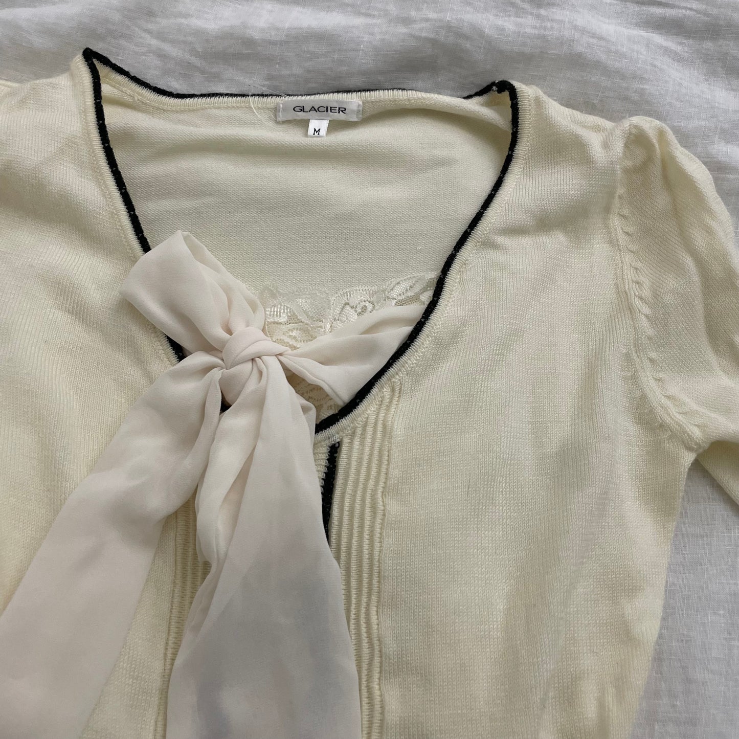 cream glacier long sleeve top with black lettuce trim and cream chiffon bow